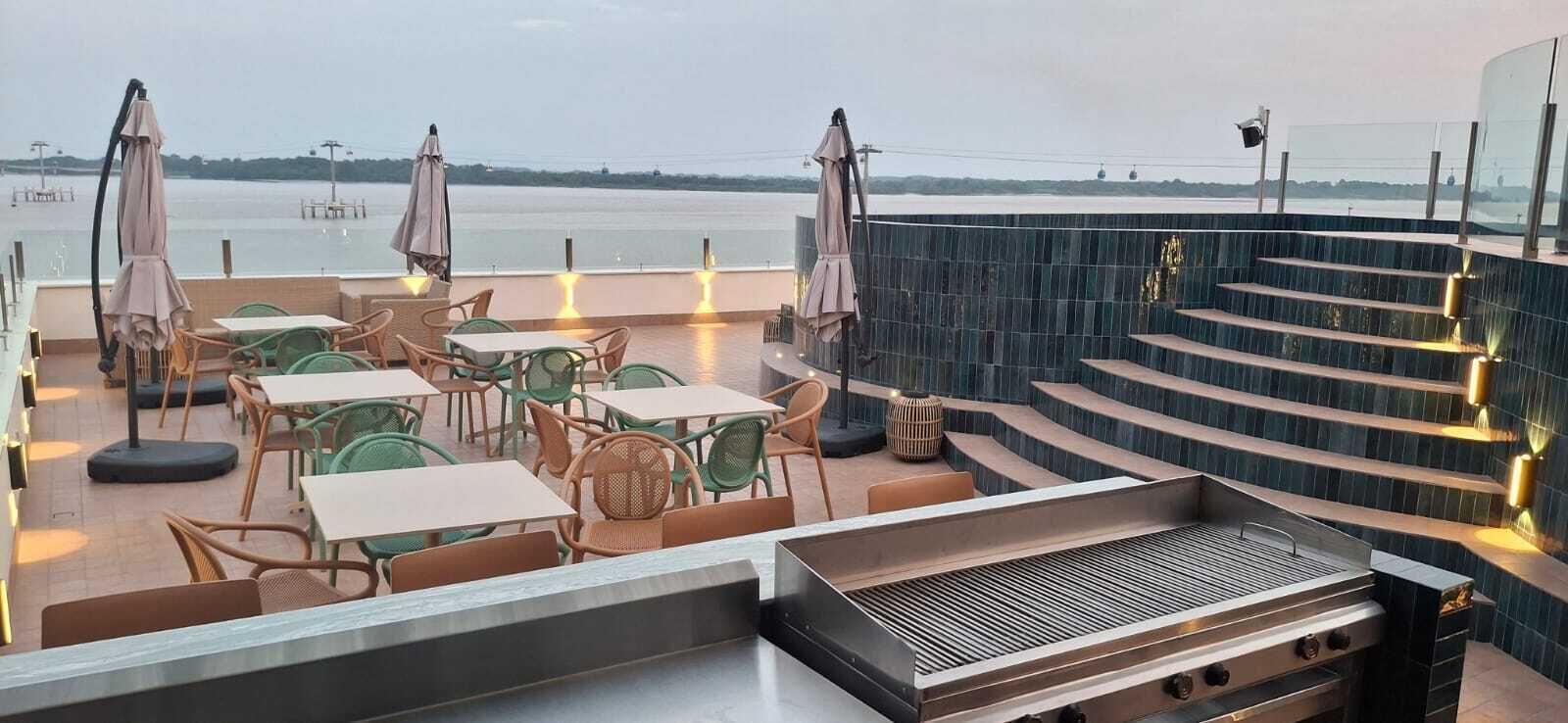 Eine Dachterrasse mit Sitzgelegenheiten im Freien, einem Grill und Blick auf das Wasser.