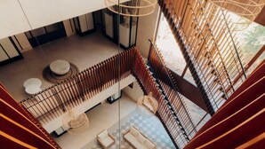 A spiral staircase leading to a lounge area with patterned flooring, seating, and hanging wicker lamps. - Hotel Río Guayas by Art Hotels Ecuador   (Guayaquil)