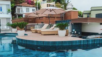 A swimming pool with lounge chairs and potted plants, surrounded by buildings.