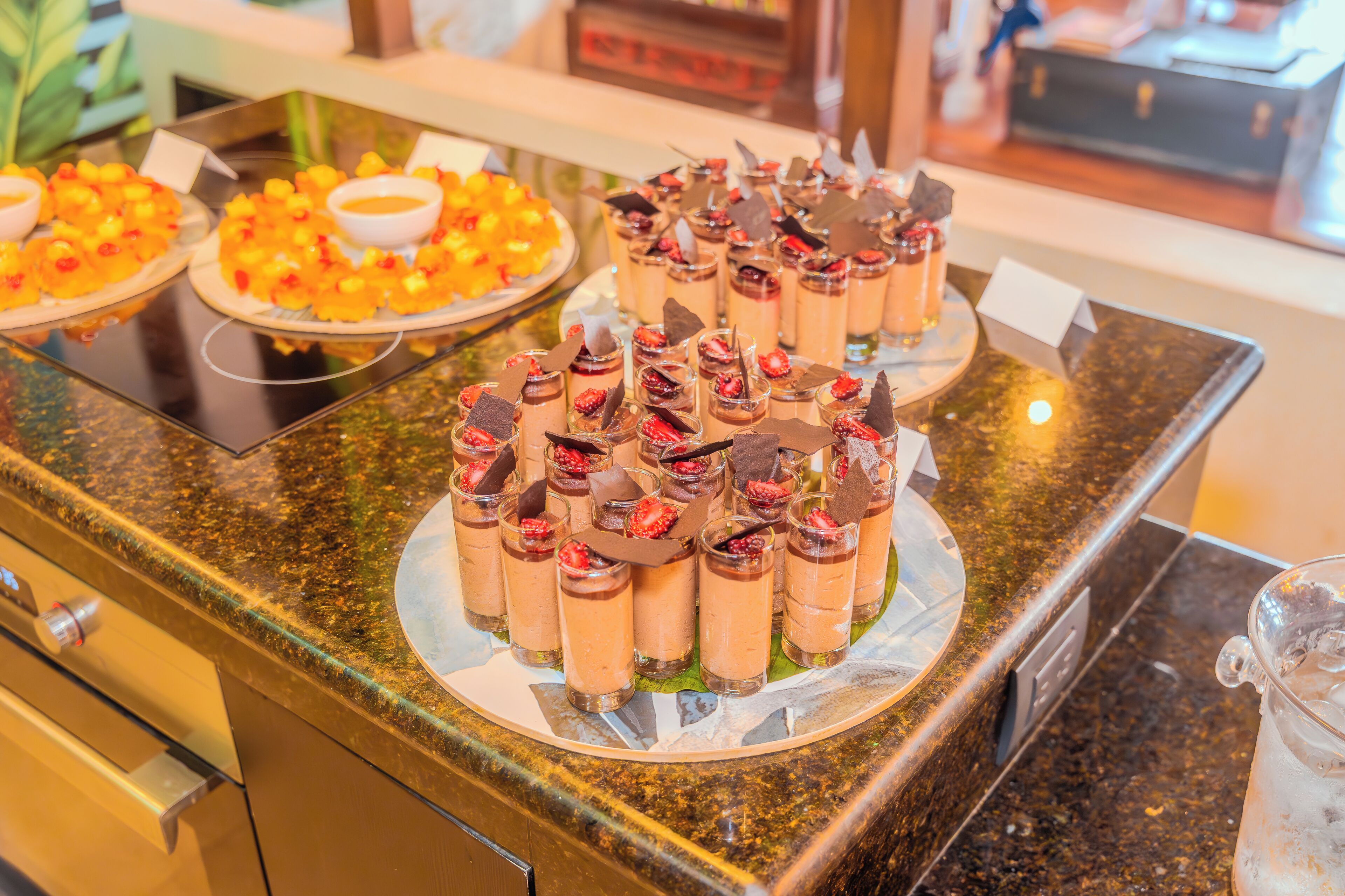 Un bufé con diversos postres, incluyendo fruta, opciones de chocolate y postres en capas.