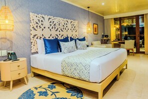 Un dormitorio con una cama grande, un cabecero decorativo, mesitas de noche, un escritorio pequeño y un rincón comedor con sillas.