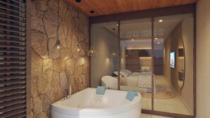 A modern bathroom with a stone wall, a freestanding bathtub, and a mirrored sliding door leading to a bedroom. - Hotel Río Guayas by Art Hotels Ecuador   (Guayaquil)