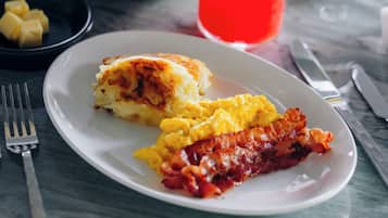 A breakfast setting with a plate of eggs, bacon, and toast, accompanied by various drinks and side dishes.