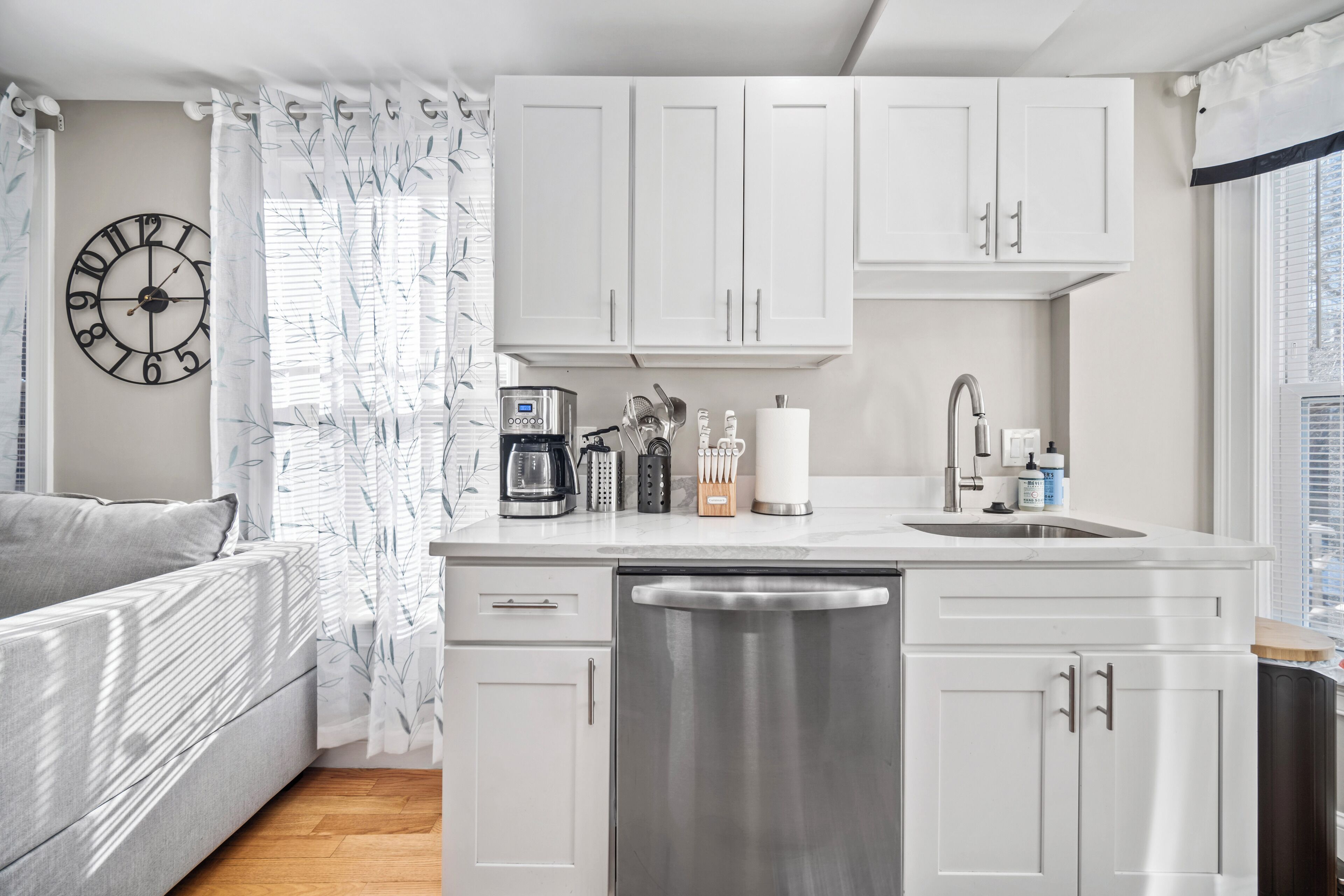 Una cocina moderna con armarios blancos, una cafetera y un lavavajillas.