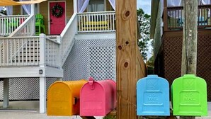 A wooden mailbox structure with colorful mailboxes in yellow, pink, blue, and green. - TWO Lake Houses, Sleeps 20, 2 HUGE gAmE rOoMs 407 (Pass Christian)