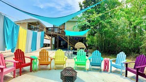 A patio area with colorful Adirondack chairs arranged around a table, a hammock, and a lantern. - TWO Lake Houses, Sleeps 20, 2 HUGE gAmE rOoMs 407 (Pass Christian)