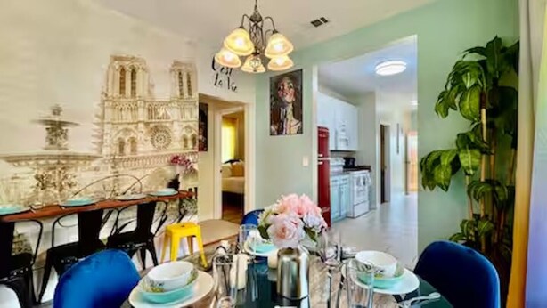 A dining area with a table set for four, a chandelier, and a decorative wall piece. - TWO Lake Houses, Sleeps 20, 2 HUGE gAmE rOoMs 407 (Pass Christian)