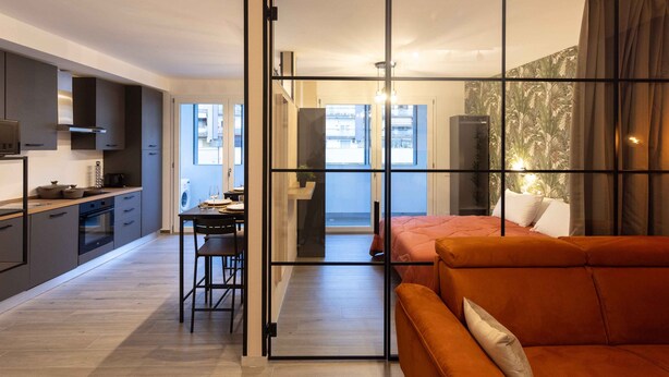 A modern apartment with a kitchen, dining area, and a living room with a sofa.