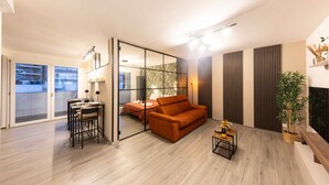 A modern living room with a sofa, a dining table, and a glass partition.