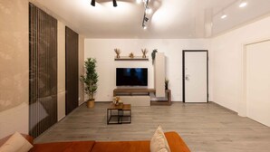 A modern living room with a flat-screen TV, a wooden coffee table, and a sofa.