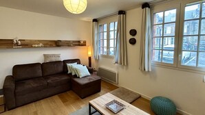 A living room with a sofa, ottoman, table, and a hanging light fixture.