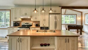 A spacious kitchen with white cabinetry, a large island with a sink, and pendant lighting.