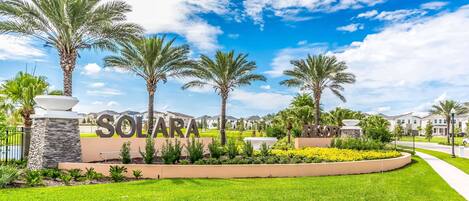 A well-maintained garden with palm trees and a sign that reads 'SOLARA RESORT'.