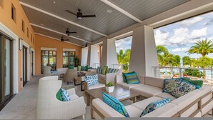 An outdoor covered patio with seating, ceiling fans, and large windows overlooking a pool area. - Spacious 7Bd Next to Clubhouse at Solara Resort (Kissimmee)