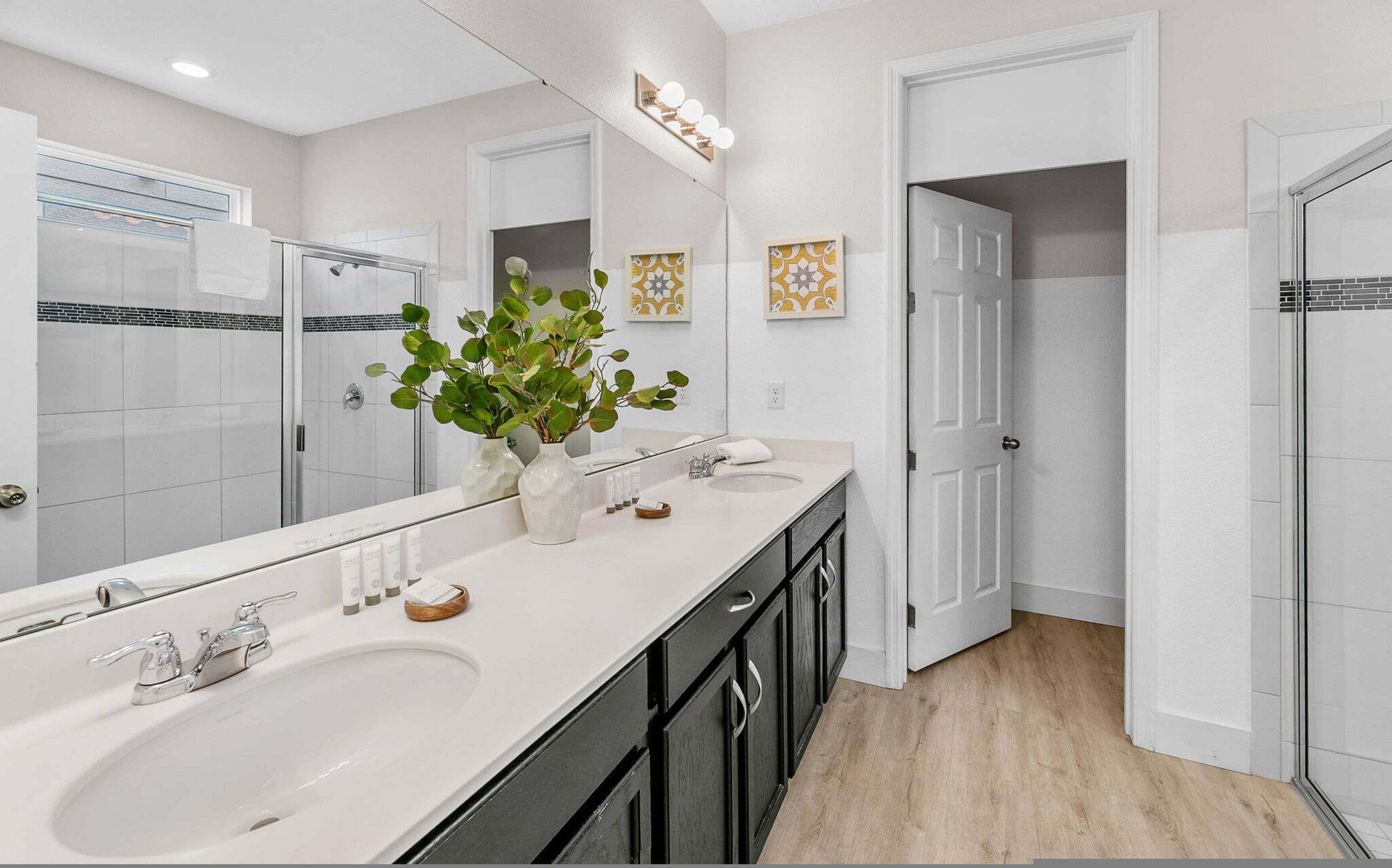 A modern bathroom with two sinks, a large mirror, and a shower.