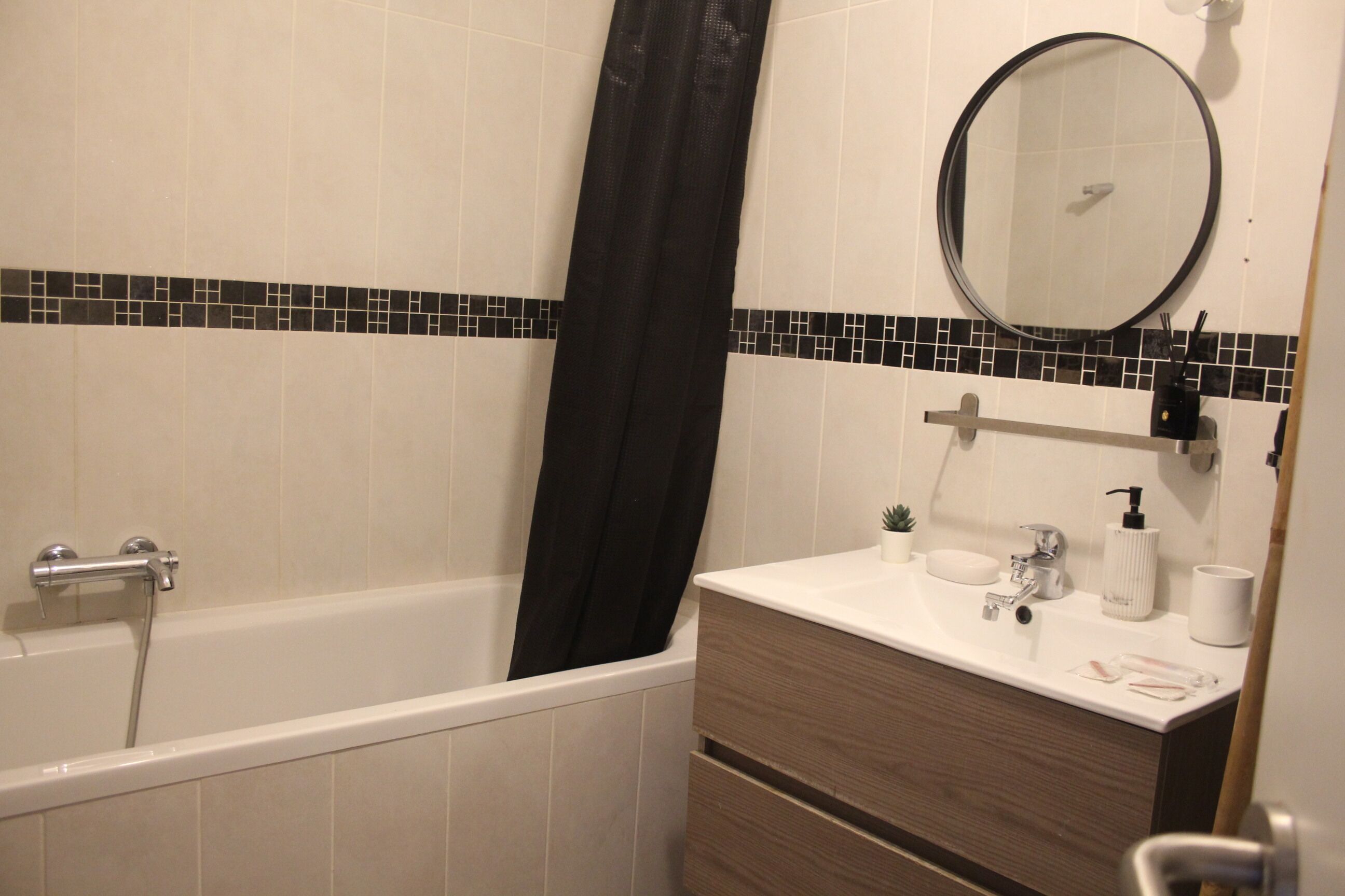 Ein Badezimmer mit Badewanne, Spiegel, Waschbecken und einem Waschtisch mit Schubladen.