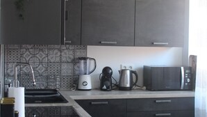 Una cocina moderna con armarios oscuros, una isla de madera y una lámpara colgante.