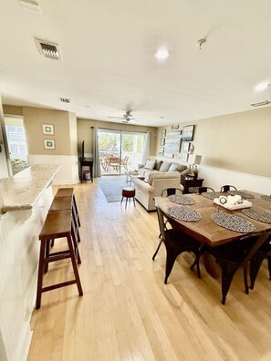 A spacious living area with a dining table, a sofa, and a kitchen counter.