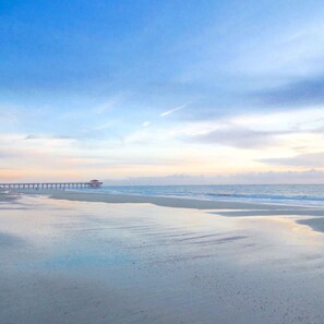 Une plage avec une jetée qui s’avance dans l’eau.