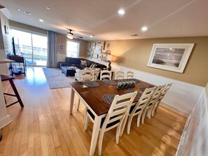 A dining area with a wooden table, white chairs, and a view of the outside.