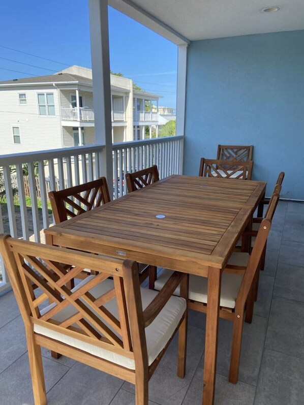 A wooden table and chairs on a balcony with a view of buildings.