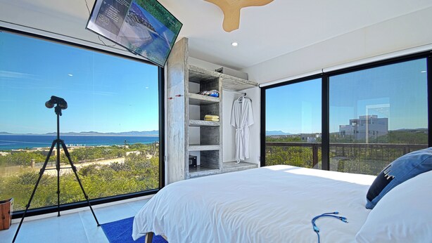 Ein Schlafzimmer mit einem großen Bett, einem an der Wand montierten Fernseher und Meerblick.