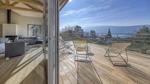 Un balcon donnant sur un paysage montagneux, un canapé et une table à manger.