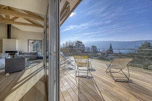A balcony with a view of a mountainous landscape, a sofa, and a dining table.
