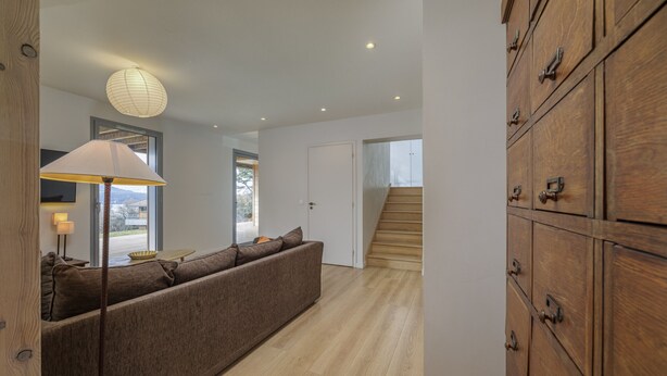 Un int érieur moderne avec un canapé, une lampe, des meubles en bois et un escalier.