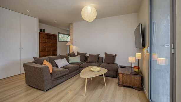 A modern living room with a sectional sofa, a small coffee table, and a television mounted on the wall. - Wooden Villa 4* (Veyrier-du-Lac)