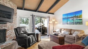 A living room with a fireplace, leather chair, sofa, and a large painting on the wall. - *Special* Lake~Hiking~Pool~Tahoe Townhome (Incline Village)