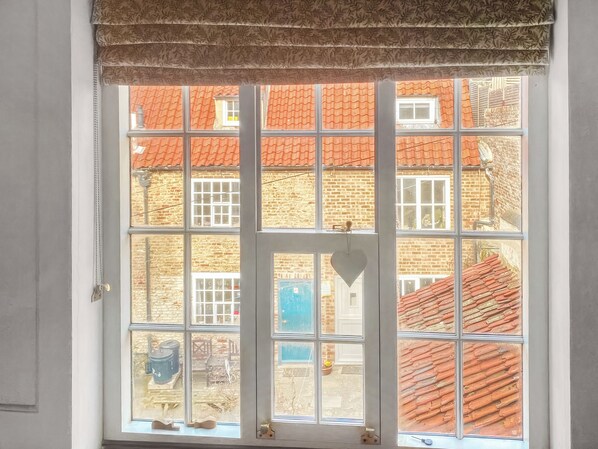 A window with a view of a brick building with red-tiled roofs.