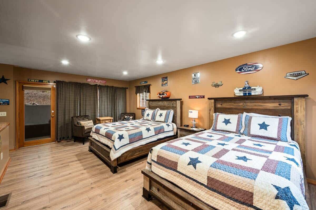 Habitación de hotel con dos camas, piso de madera, un emblema de Ford y un emblema de Chevrolet en la pared.