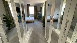 Une chambre d’hôtel avec deux lits, un bureau, une chaise et une plante en pot.