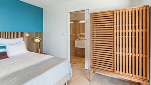 A hotel room with a bed, a wooden headboard, a nightstand, a wall-mounted lamp, and a wooden wardrobe. - Cézembre (Le Diamant)