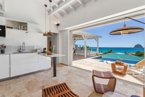 Enjoy a serene ocean view from the balcony, complete with outdoor furniture and a pergola, adjacent to a well-appointed kitchen.
