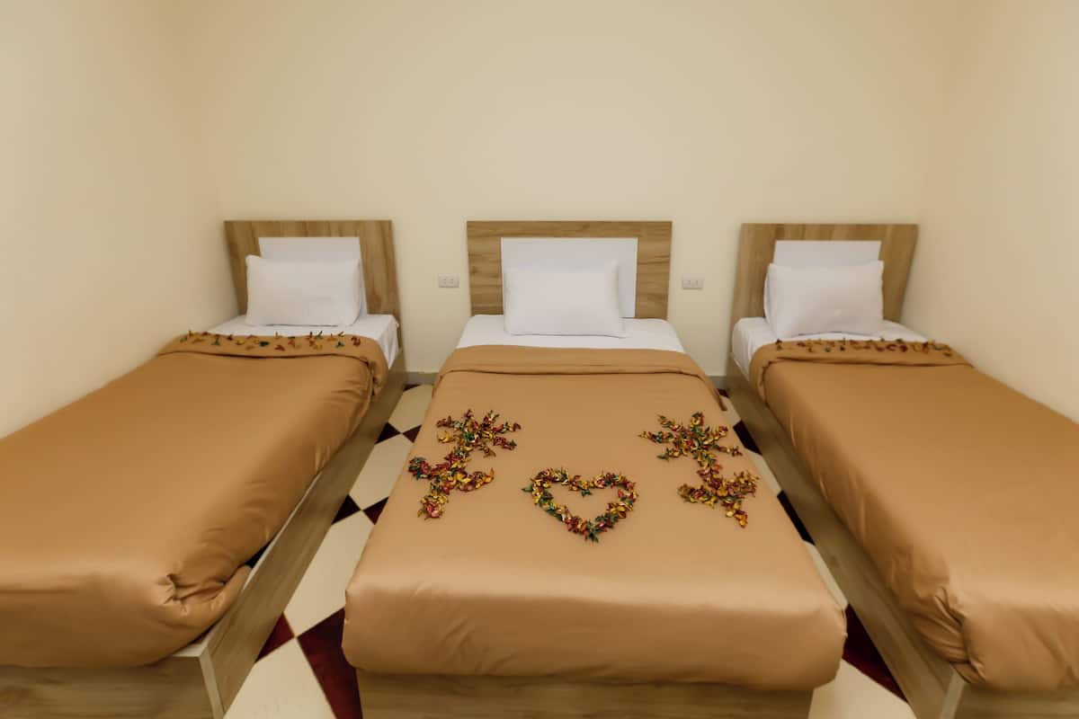 Tre letti singoli con testiere in legno, biancheria beige e composizioni floreali decorative sui letti.