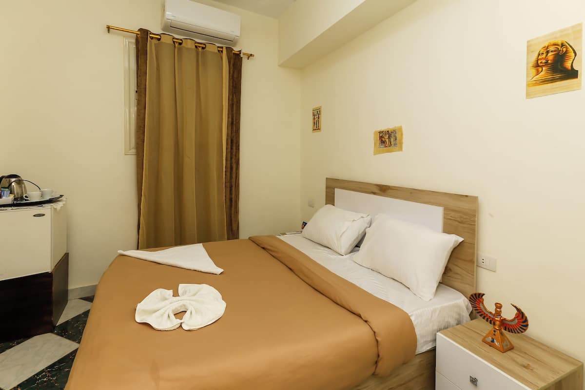 Una camera d'albergo con un letto, un comodino, una scrivania e una tenda.