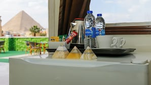 A table with a tray containing a coffee pot, two water bottles, a cup, and three pyramid-shaped containers. - Nefertiti pyramids (Giza)