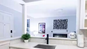 A modern kitchen with white cabinetry, a stainless steel dishwasher, and a countertop with a sink and decorative items. - Charming, bungalow + hot tub in NODA district of Charlotte. 10 min f/uptown. (Charlotte)