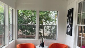A sunroom with two orange chairs, a blue ottoman, and a hanging light fixture. - Charming, bungalow + hot tub in NODA district of Charlotte. 10 min f/uptown. (Charlotte)