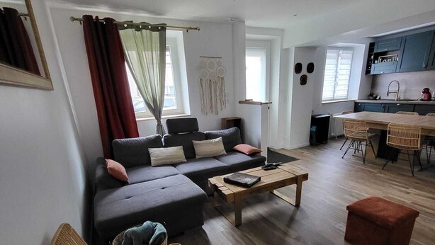 A modern living room with a sofa, chairs, a coffee table, and a kitchen area in the background. - Renovated and elegant Ledoux Land house near Disney and 45 min from Paris (Bailly-Romainvilliers)