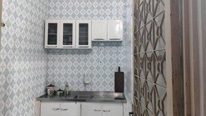 A compact kitchen with patterned tiles, white cabinets, and a metal backsplash.