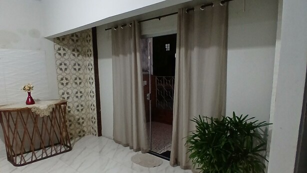 A room with a tiled floor, a small table with a vase, a potted plant, and a sliding door leading to another room.