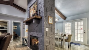 Una sala de estar con chimenea de piedra, piso de madera y comedor con mesa y sillas.
