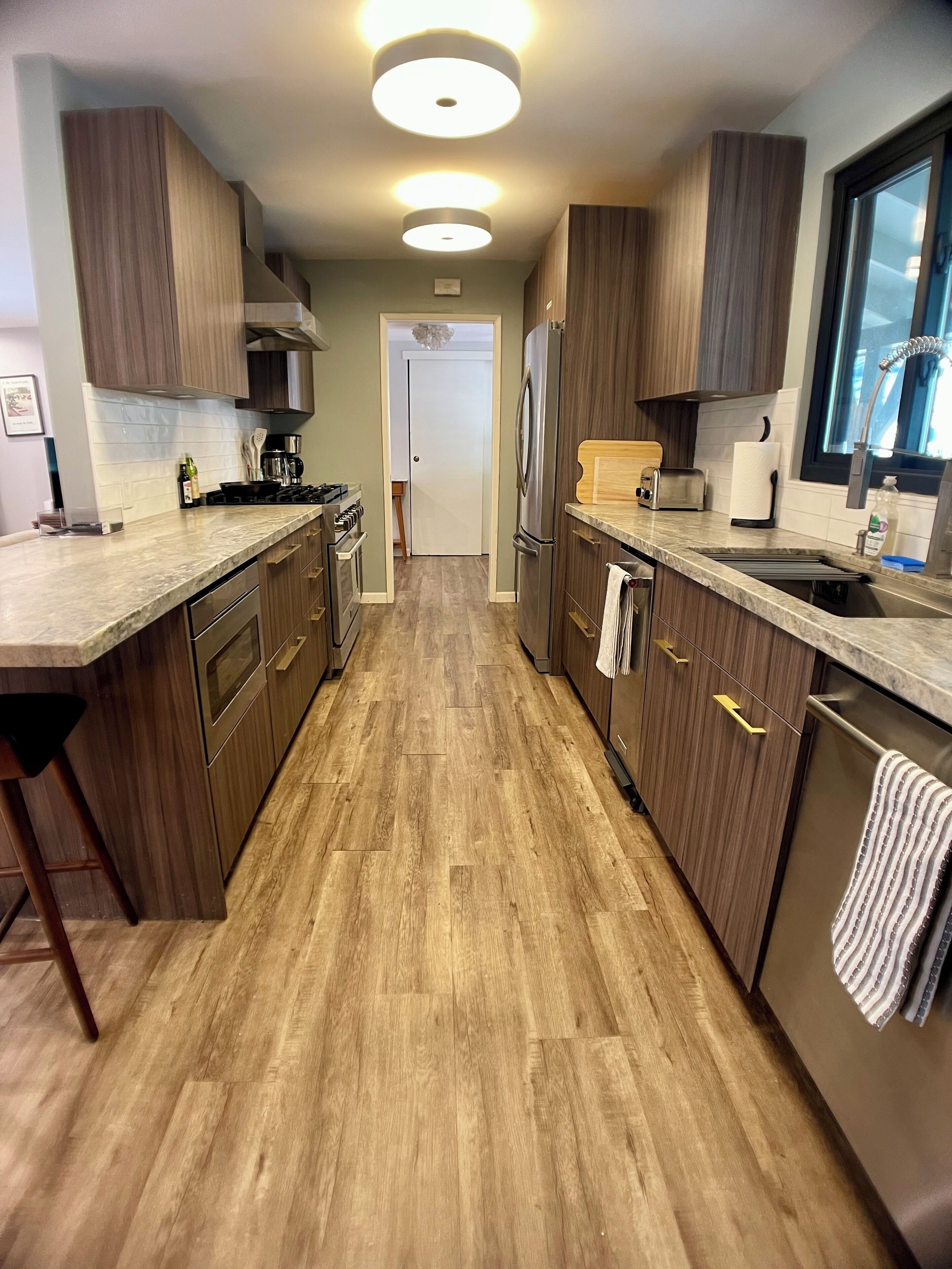 Une cuisine moderne avec des meubles en bois, des appareils en acier inoxydable et un plan de travail en marbre.