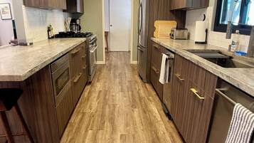 Une cuisine moderne avec des meubles en bois, des appareils en acier inoxydable et un plan de travail en marbre.