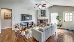 A spacious living room with hardwood flooring, a gray sofa, a coffee table, and a fireplace.