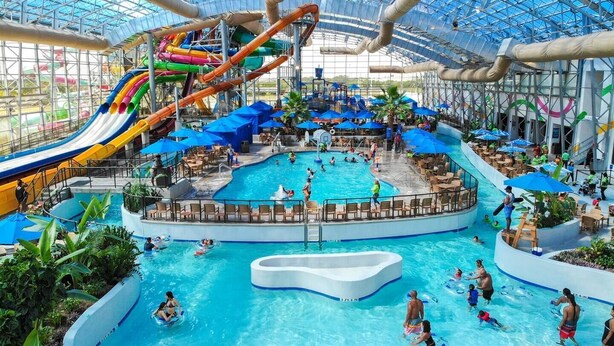 An indoor water park with multiple slides, a central pool, and lounge areas.