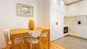 A modern kitchen with white cabinets, a dining table with chairs, and a hanging light fixture. - Arroios Concept VI by Homing (Lisbon)
